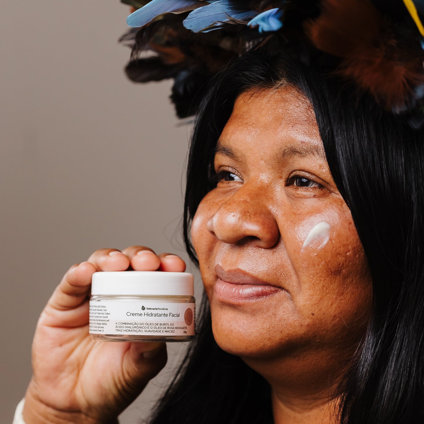 mulher segurando pote de Creme facial com bioativos amazônicos de buriti,