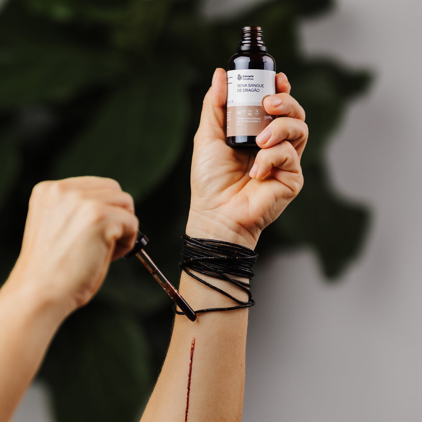 mão segurando frasco de Látex resinoso natural vegetal puro