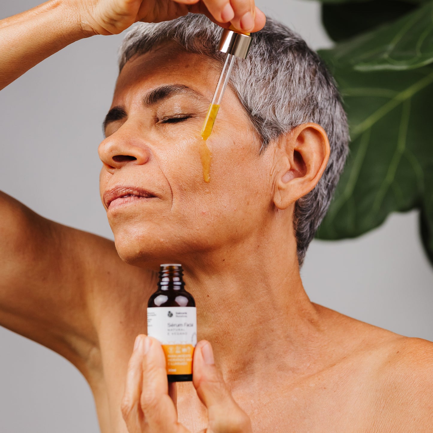 mulher passando óleo no rosto Sérum facial com bioativos amazônicos de óleo de buriti e óleo de babaçu. 