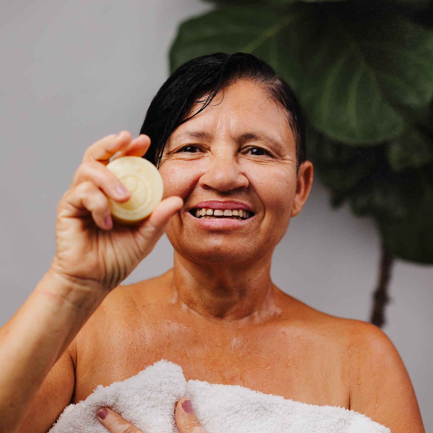 mulher tomando banho Shampoo sólido com bioativos amazônicos de buriti, manteiga de murumuru e óleo de babaçu. 