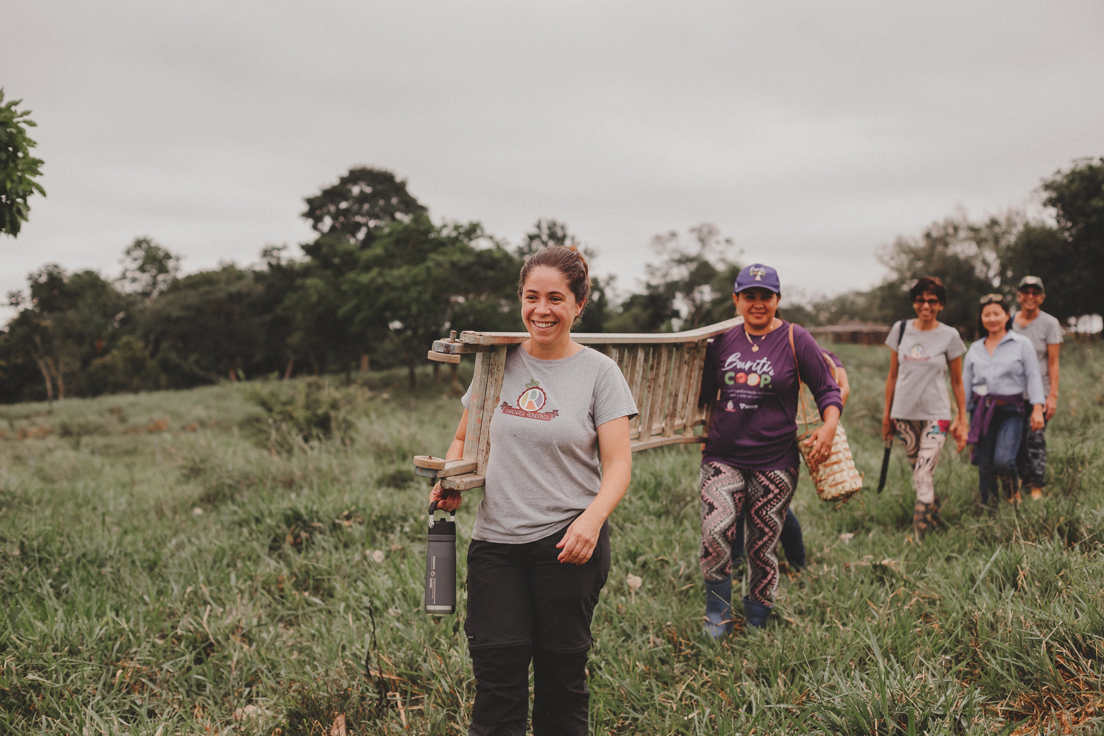 mulheres carregando escada no meio do pasto
